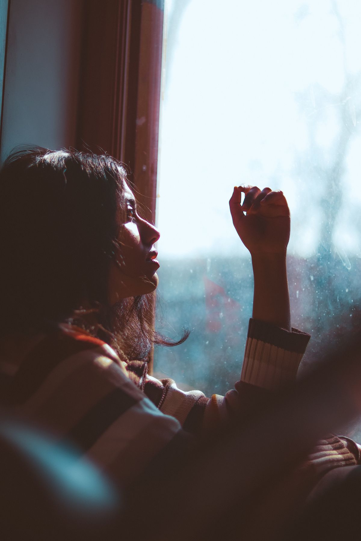Mujer pensativa junto a una ventana