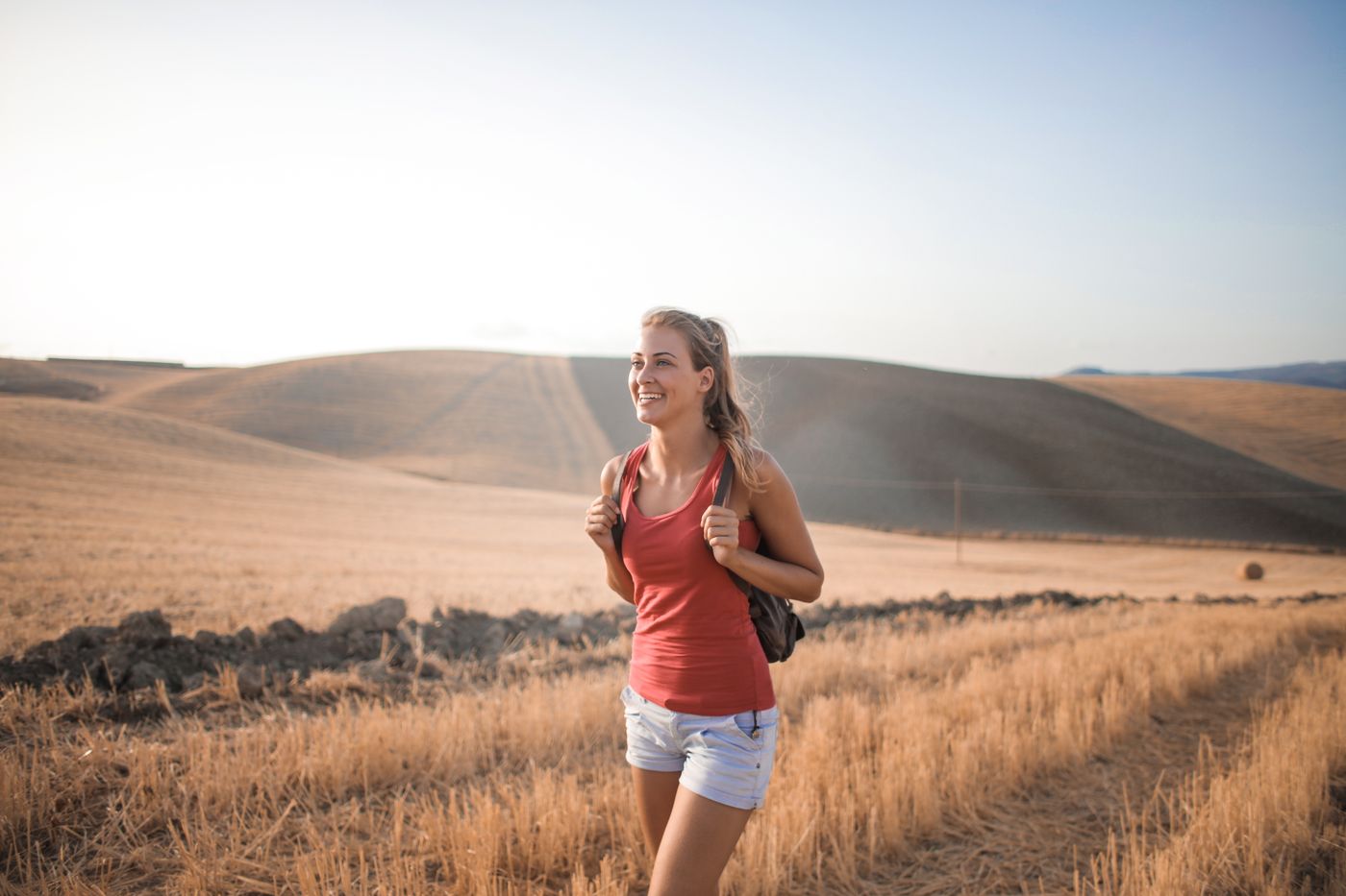 Mujer caminando por un campo abierto a pleno sol